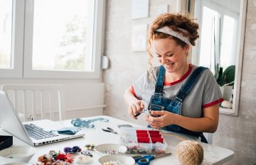 Woman seated at a table working on a craft project